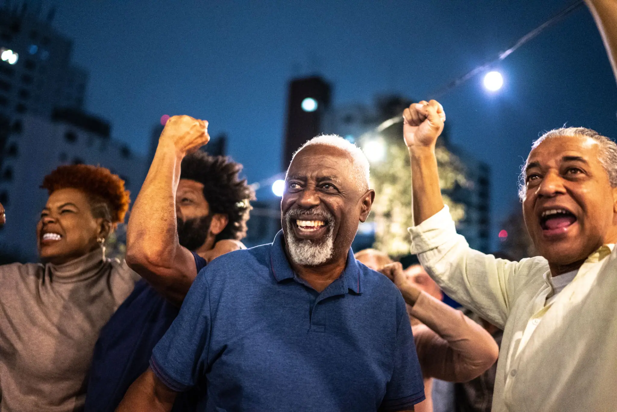 Group of joyful adults cheering outdoors at night