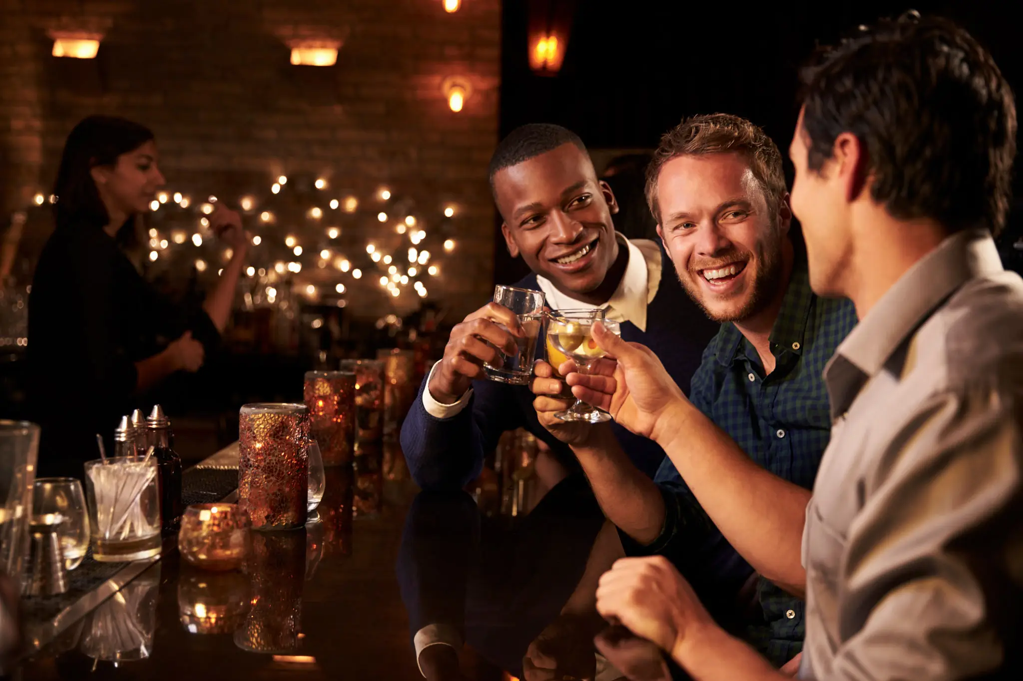 Three friends clinking glasses at a bar