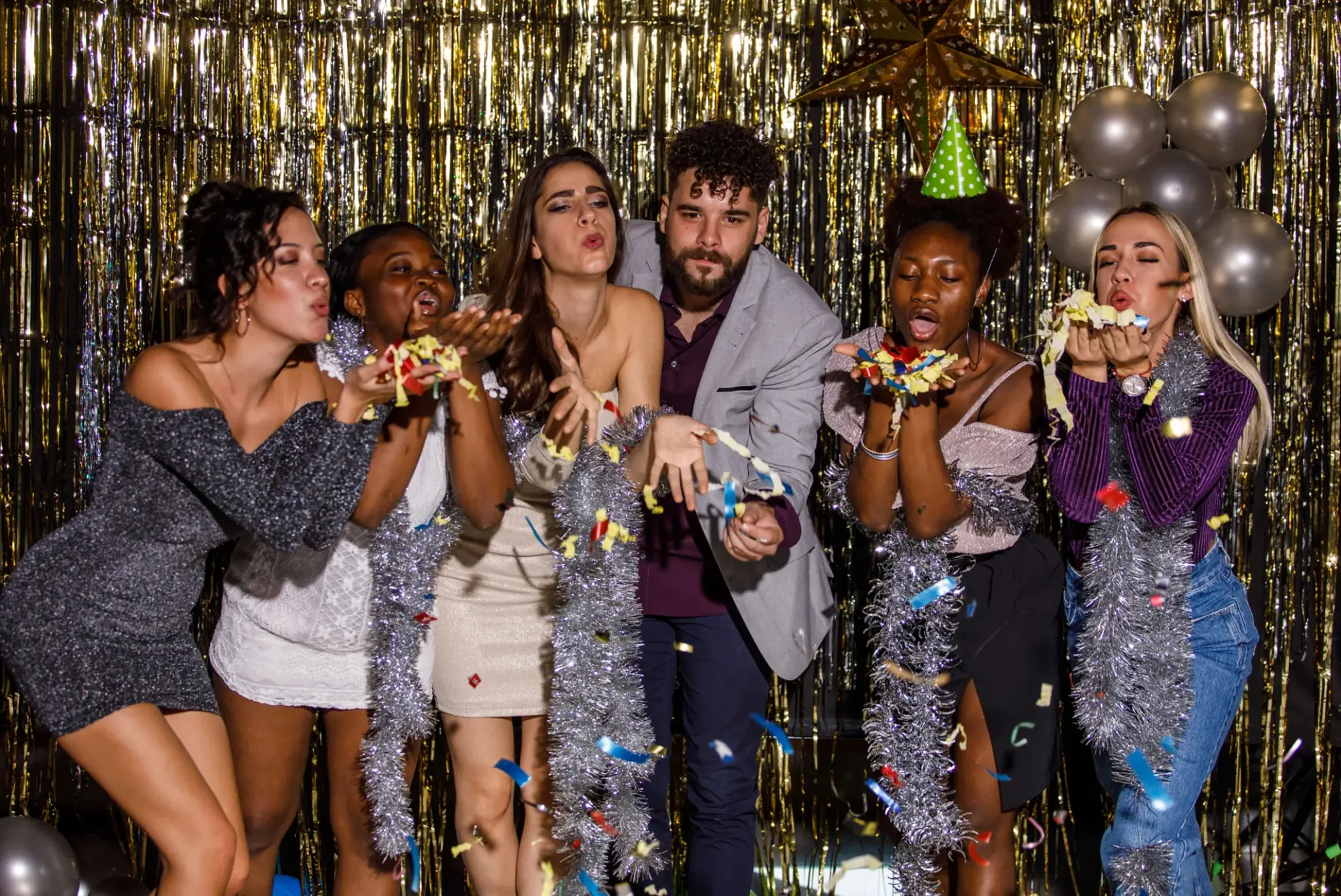 Group of friends blowing confetti at party